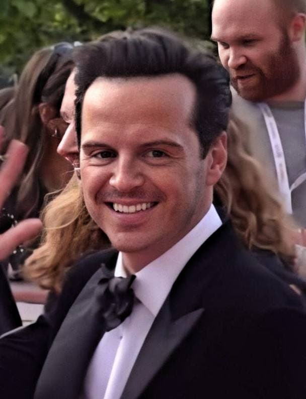 Andrew Scott in a black dinner jacket and bow tie, smiling at the camera in a crowd