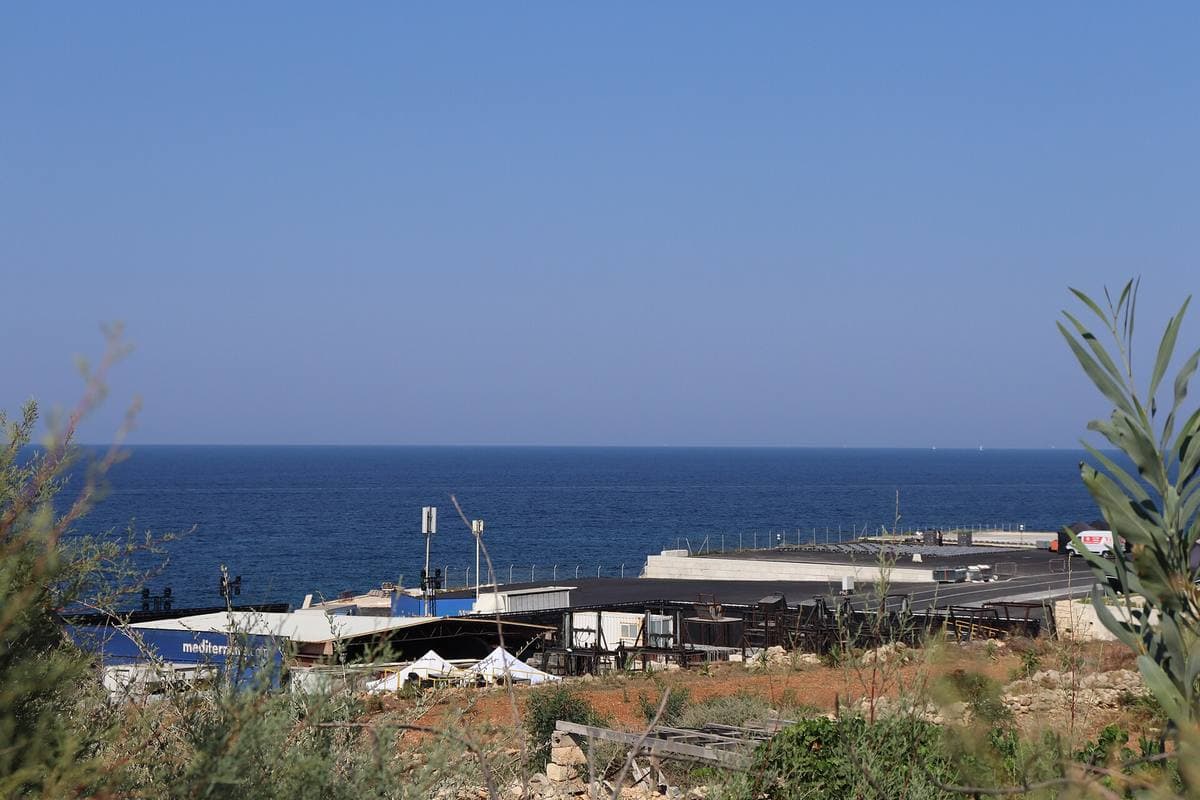 A wide flat water tank with a painted sky backdrop beside the sea
