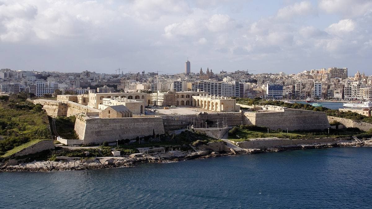 A honey-coloured stone fort on low walls above harbour water