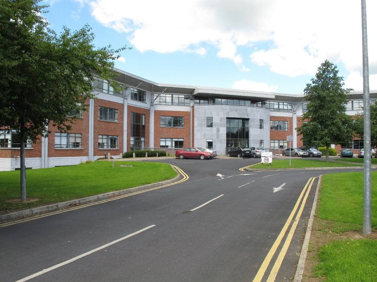 A low modern office building beside a lawn and trees