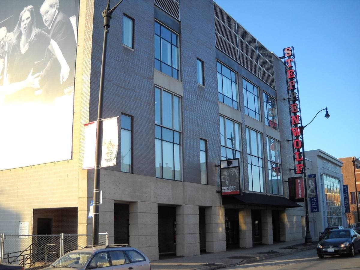 A modern theatre building on a city street with a tall vertical Steppenwolf sign