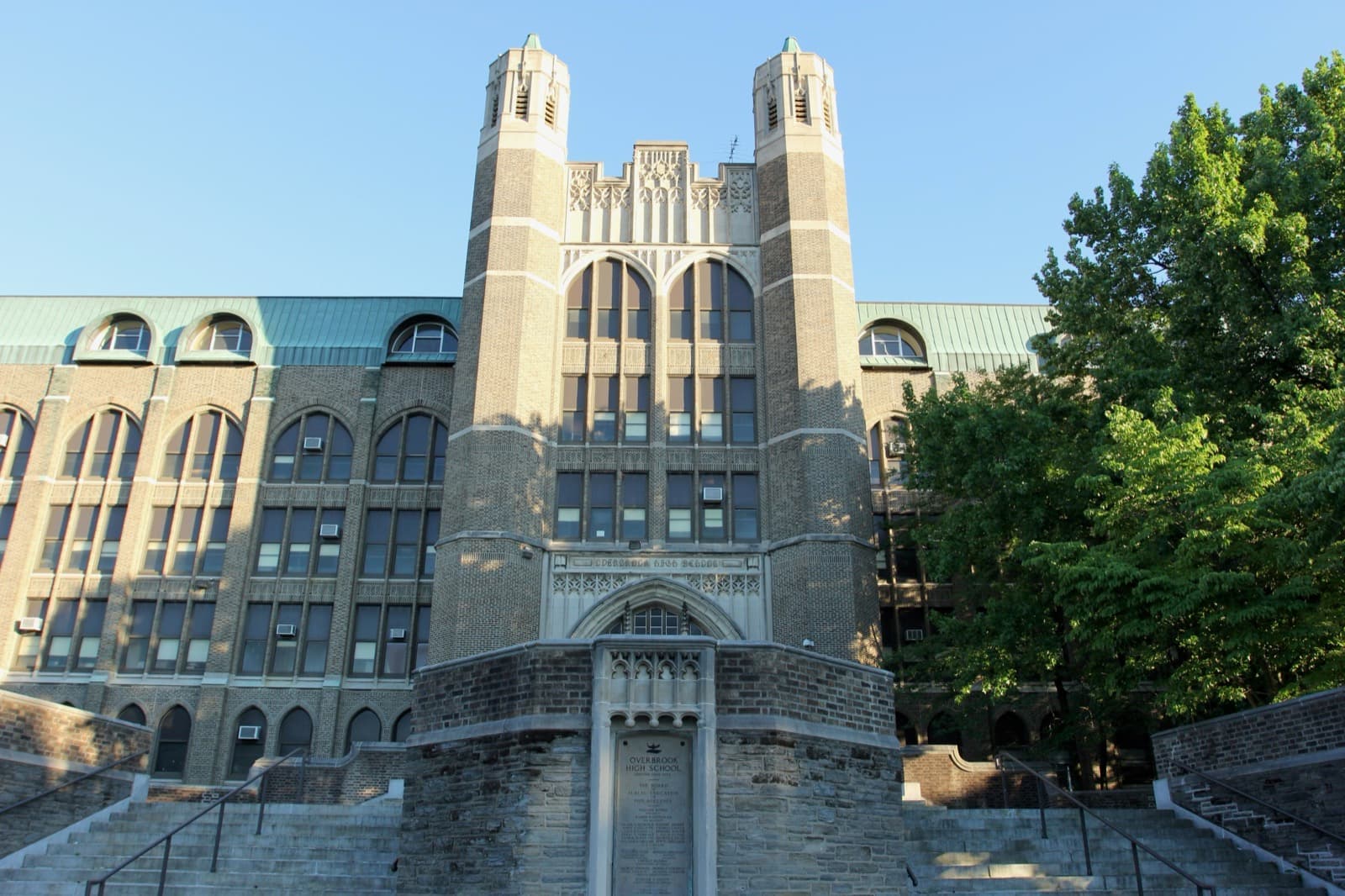 The towered front of Overbrook High School behind trees