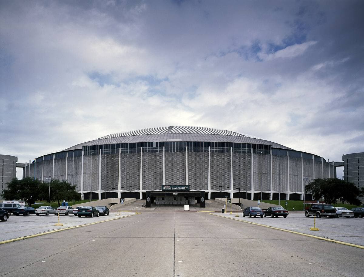 The low round dome of the Astrodome at the end of an empty approach road under cloud