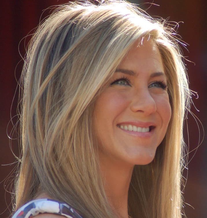 Jennifer Aniston smiling, hair loose, in a dark top
