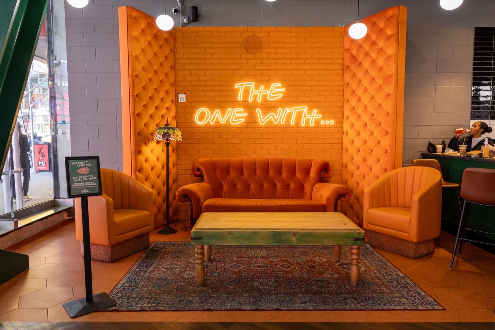 An orange velvet sofa in a coffee house, with framed art behind