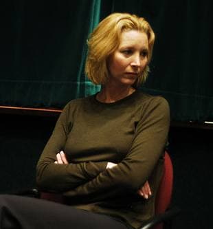 Lisa Kudrow with a fair bob, arms folded, in a dark jumper