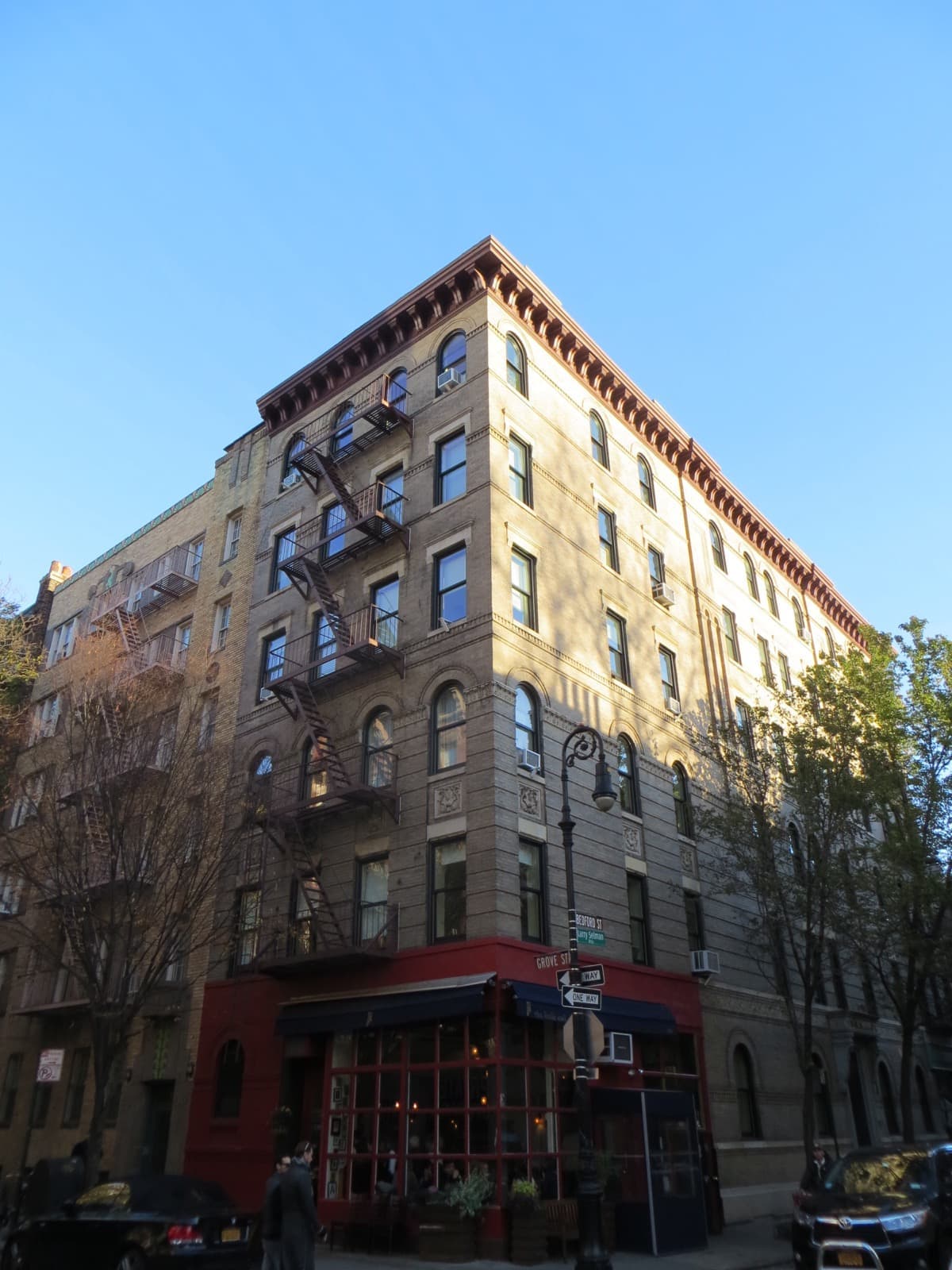 The corner of a brick apartment building seen from below against a blue sky