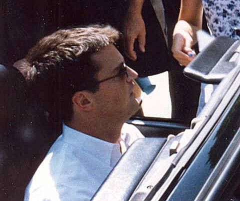 Matthew Perry in sunglasses and a white shirt, sitting in a convertible