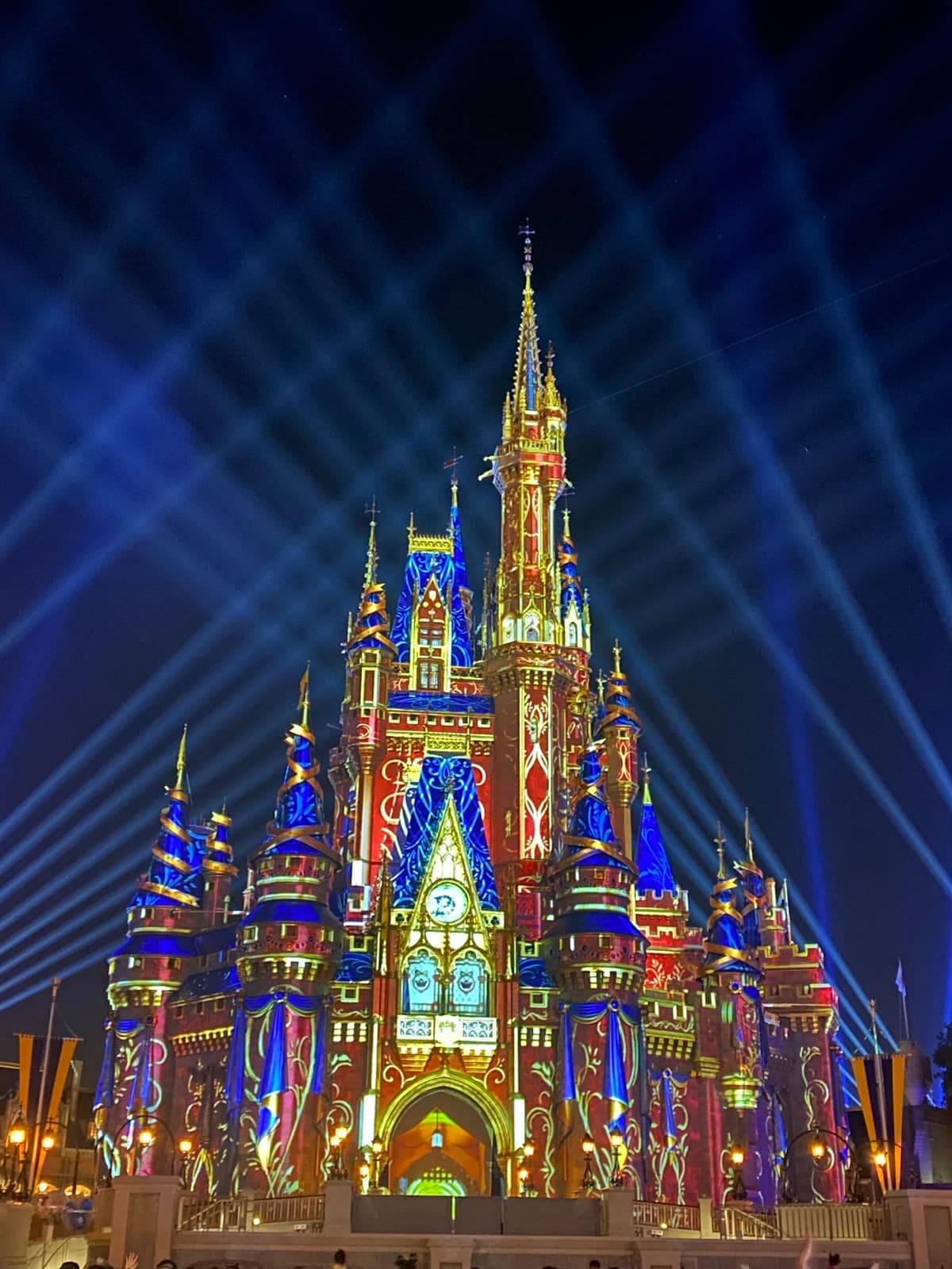 Cinderella Castle covered in bright coloured projected patterns against a night sky