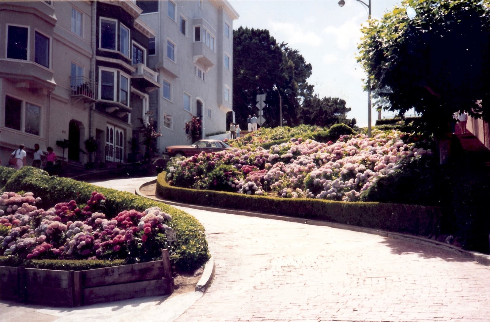 A 1987 colour photograph of cars winding down the hairpin bends of Lombard Street between hedges