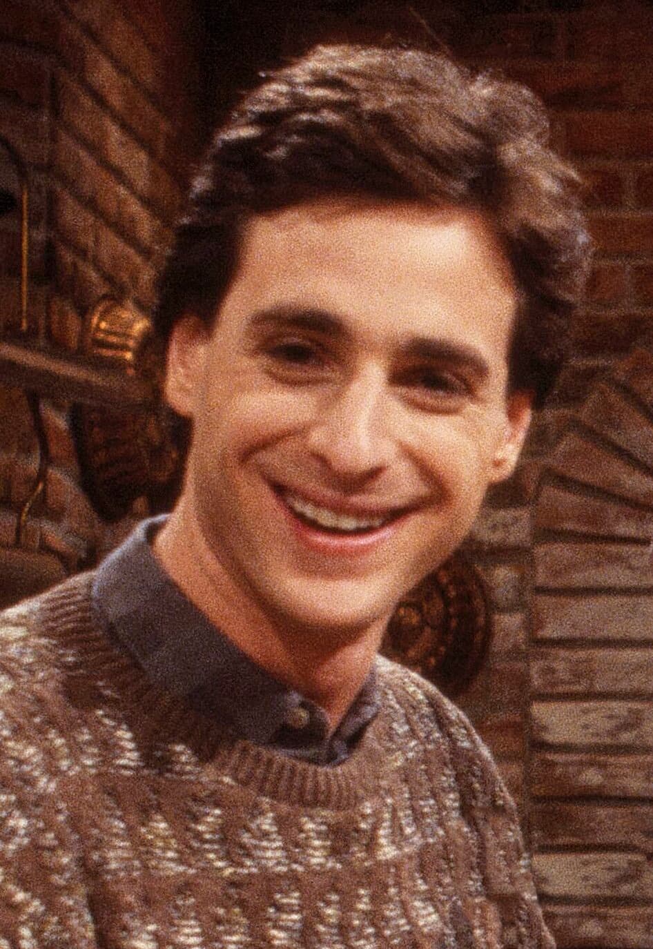Bob Saget smiling in a jacket and tie, a black-and-white portrait