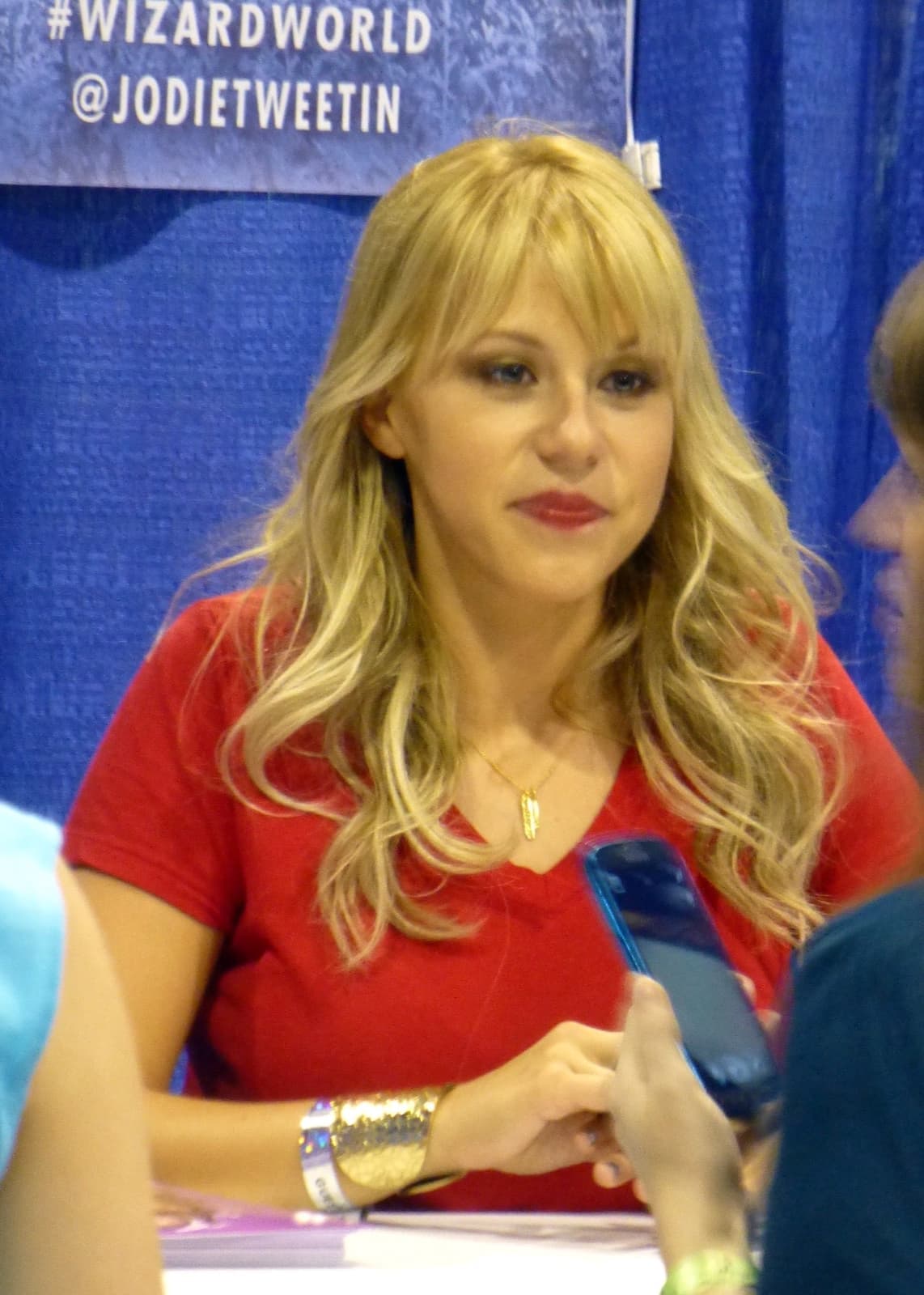 Jodie Sweetin smiling at a convention panel table