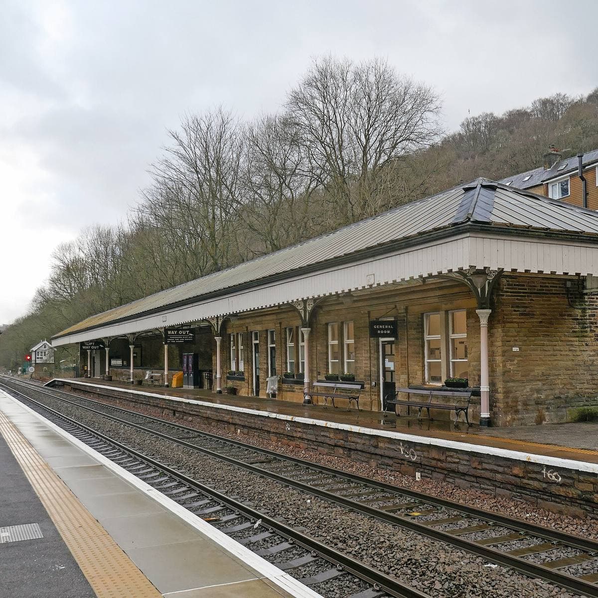 A long station canopy with fretwork edging above an empty platform