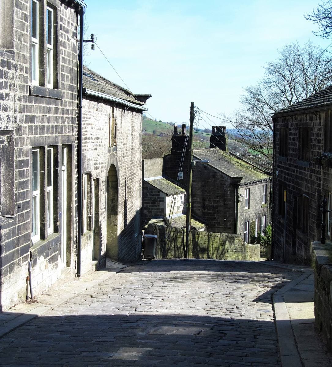 A narrow cobbled street climbing between dark stone cottages