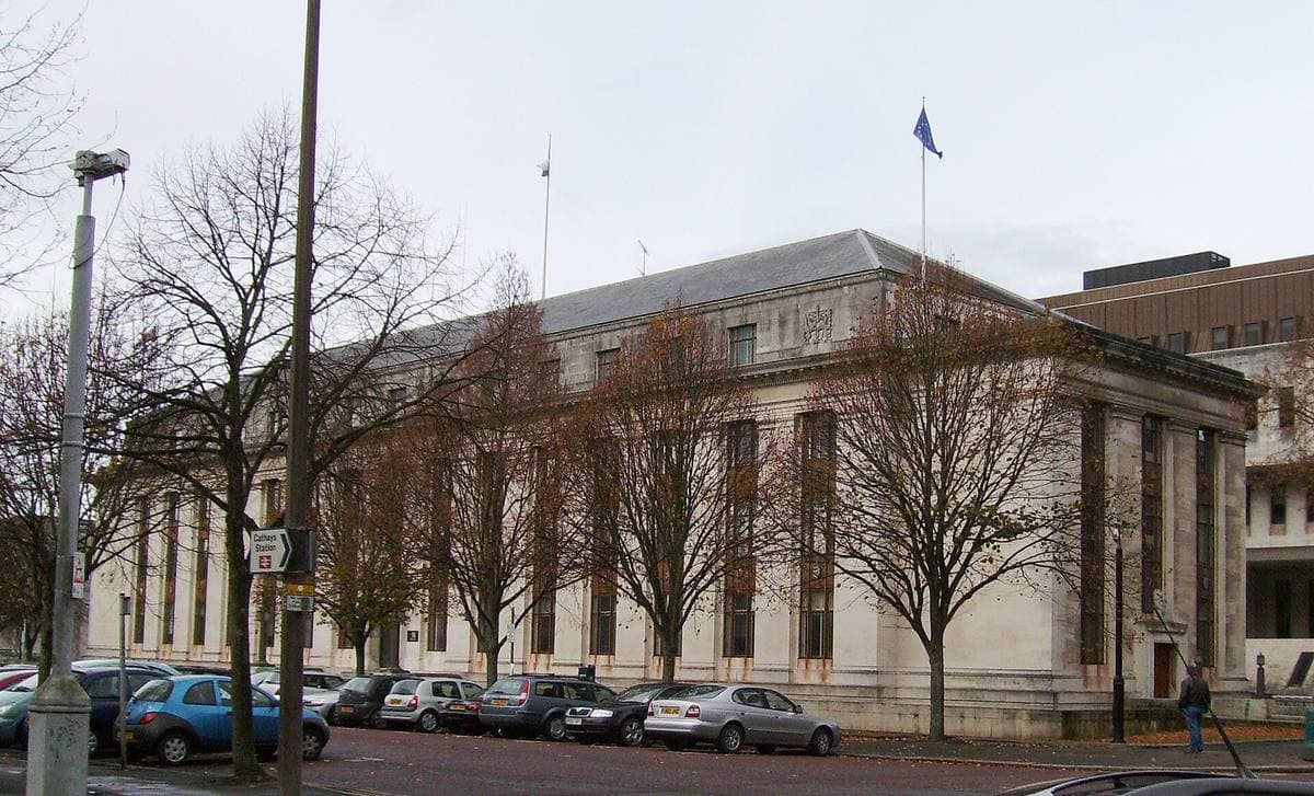 A large white stone government building with a lawn in front