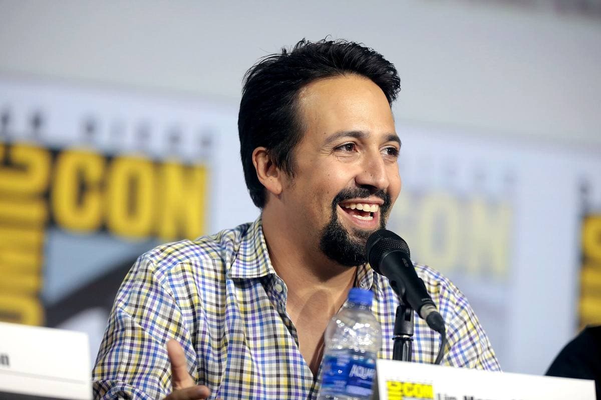 A man with a beard and swept-back hair speaking on a panel