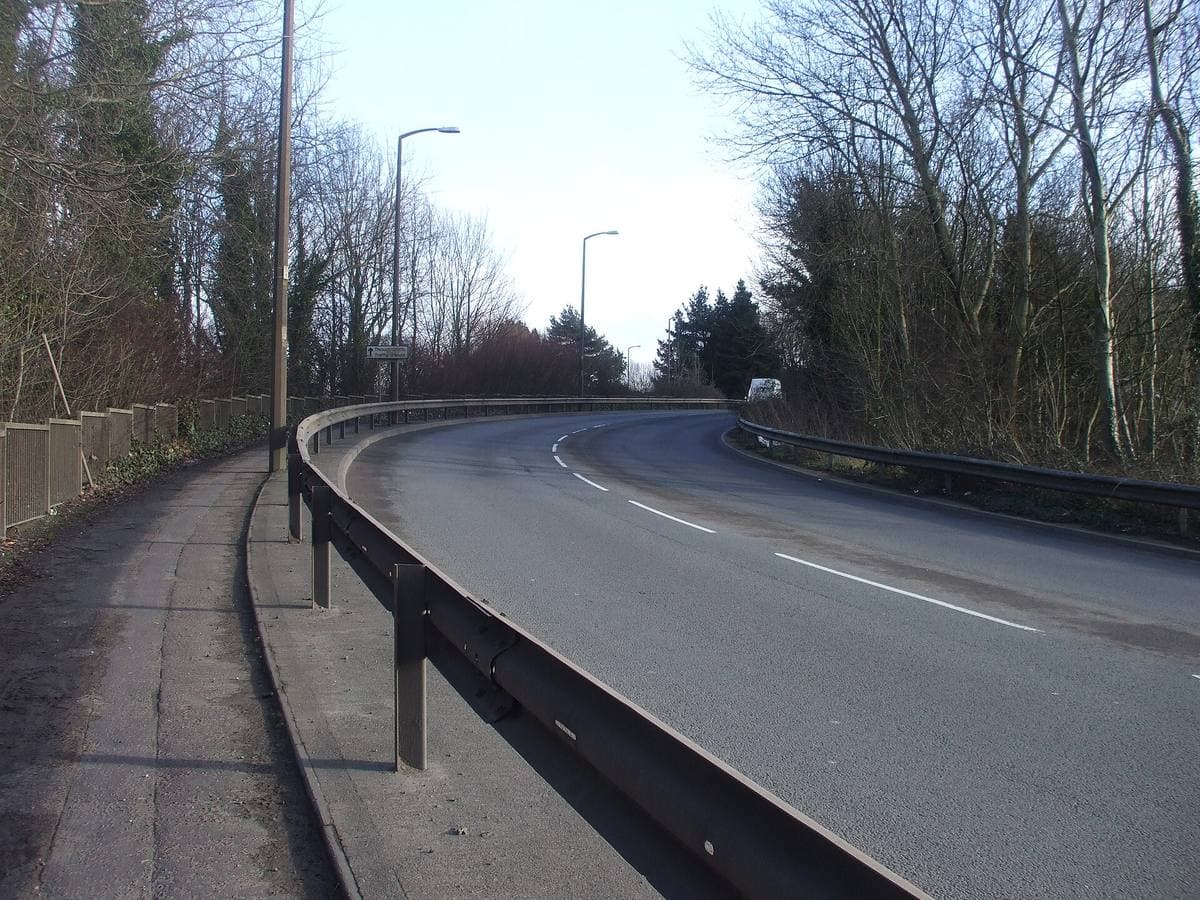 A wide road with industrial units and street lights