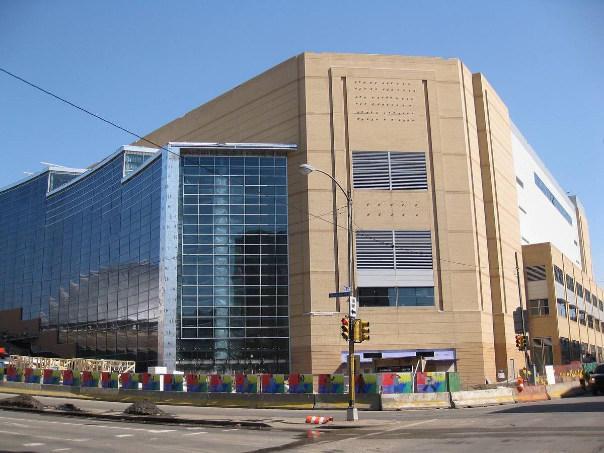 A large new arena of glass and brick behind construction fencing