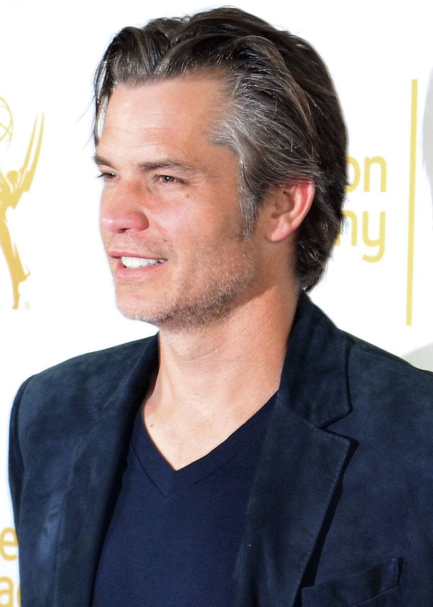 A man with short dark hair in a dark jacket, smiling
