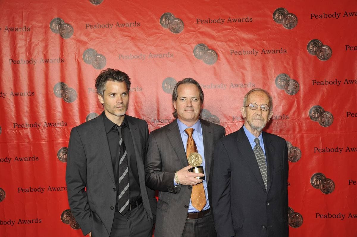 Three men in suits standing together at an awards luncheon