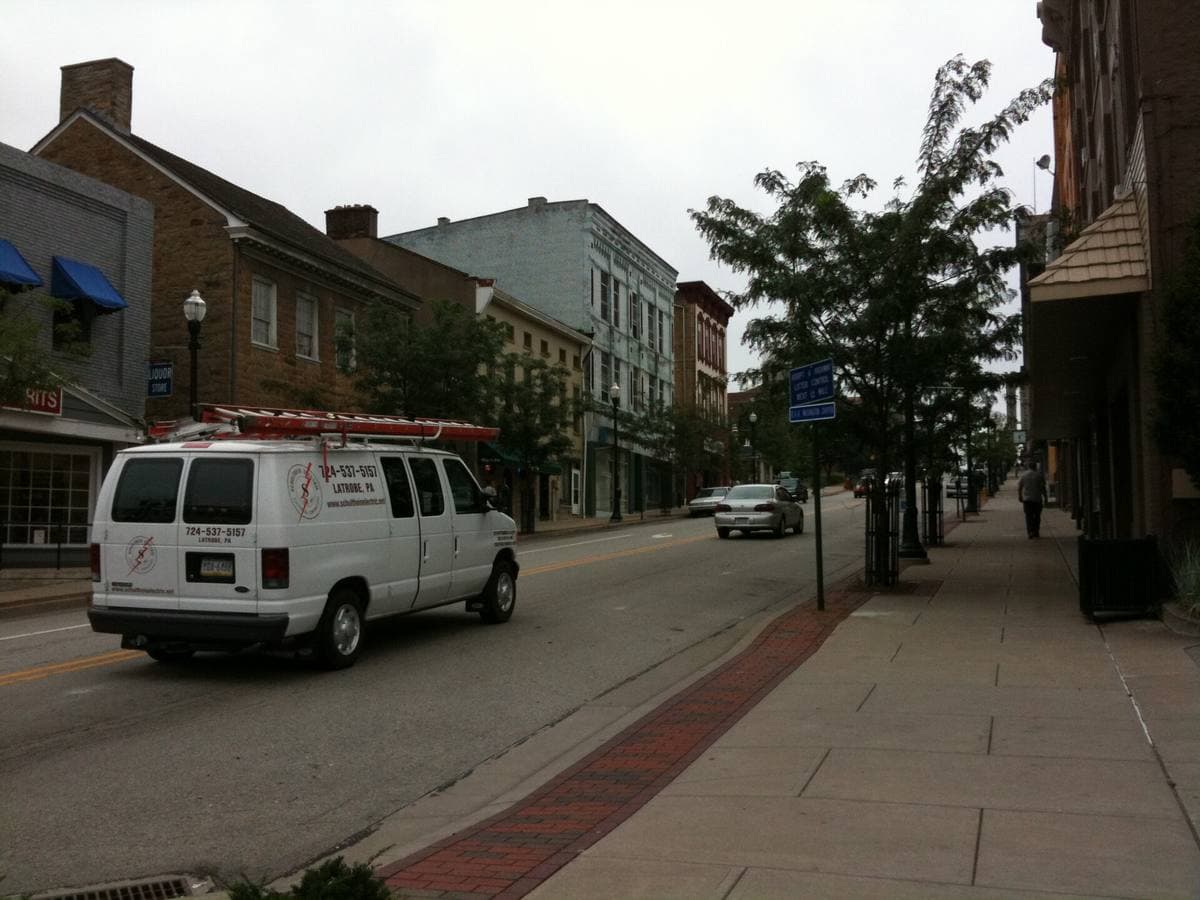 A main street with a stone eighteenth-century house beside a grey brick shop