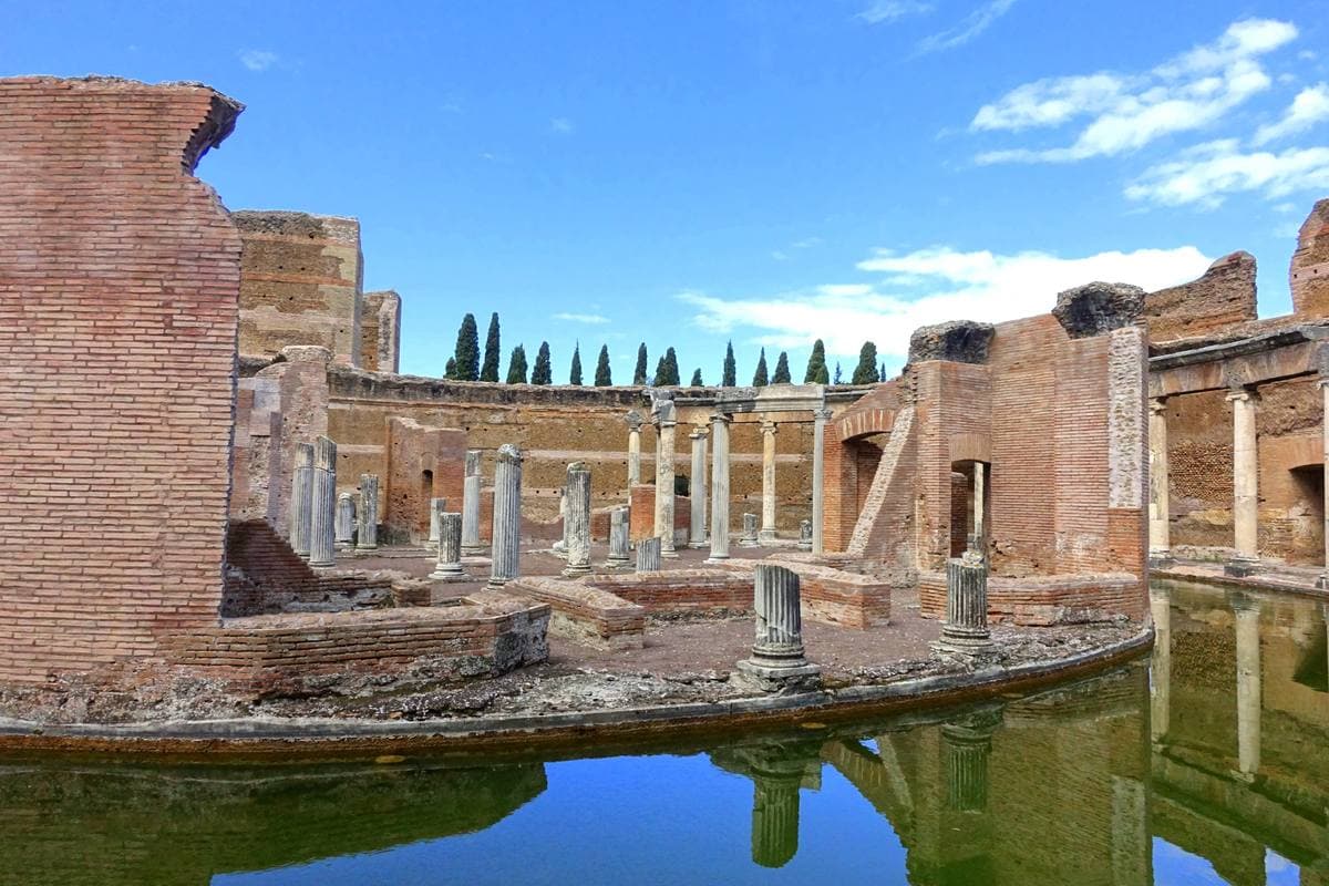 A ring of white marble columns around a circular moat inside brick ruins