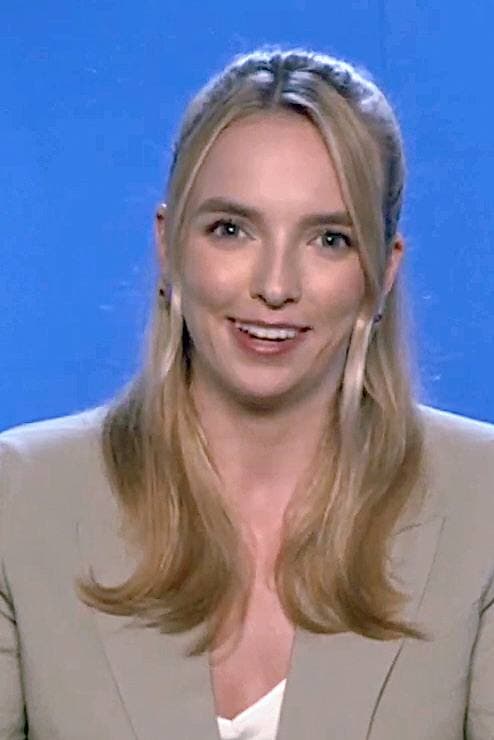 Jodie Comer, fair hair tied back, looking into the camera
