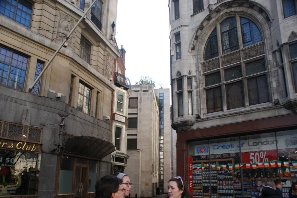 A narrow back street sloping away between tall stone office buildings