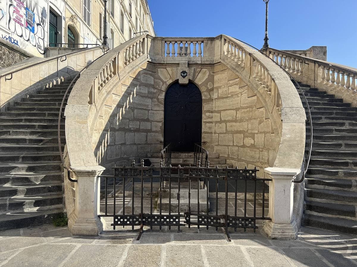 A wide stone double staircase climbing between balustrades to a landing