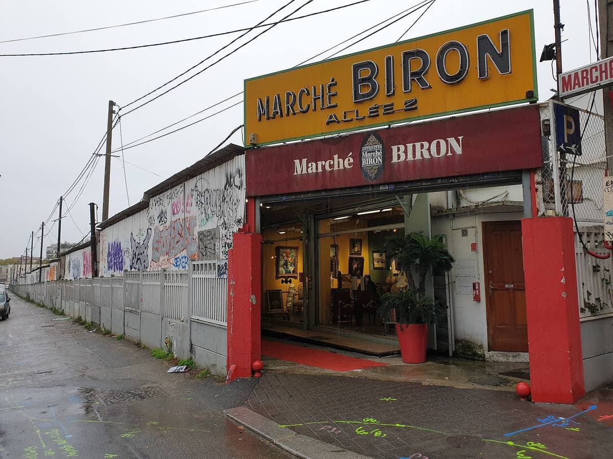A yellow and red Marché Biron sign over a market entrance on a wet street