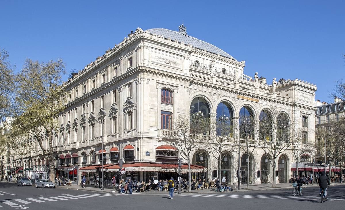 A pale stone theatre with arched windows on a street corner