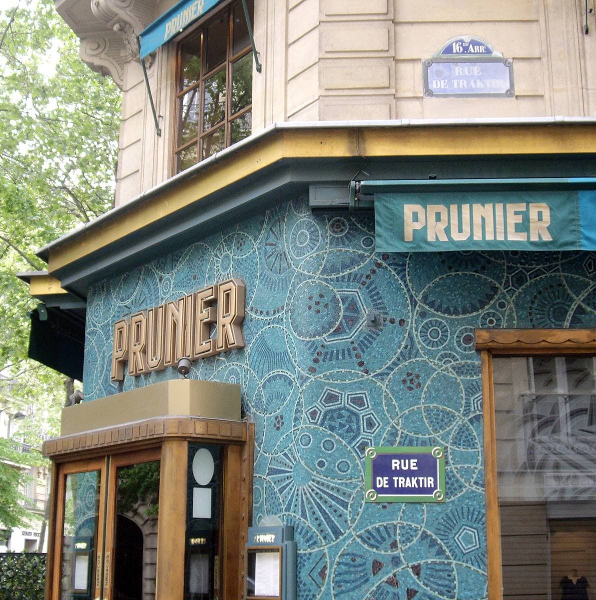 A restaurant front faced in blue mosaic with PRUNIER in gold letters