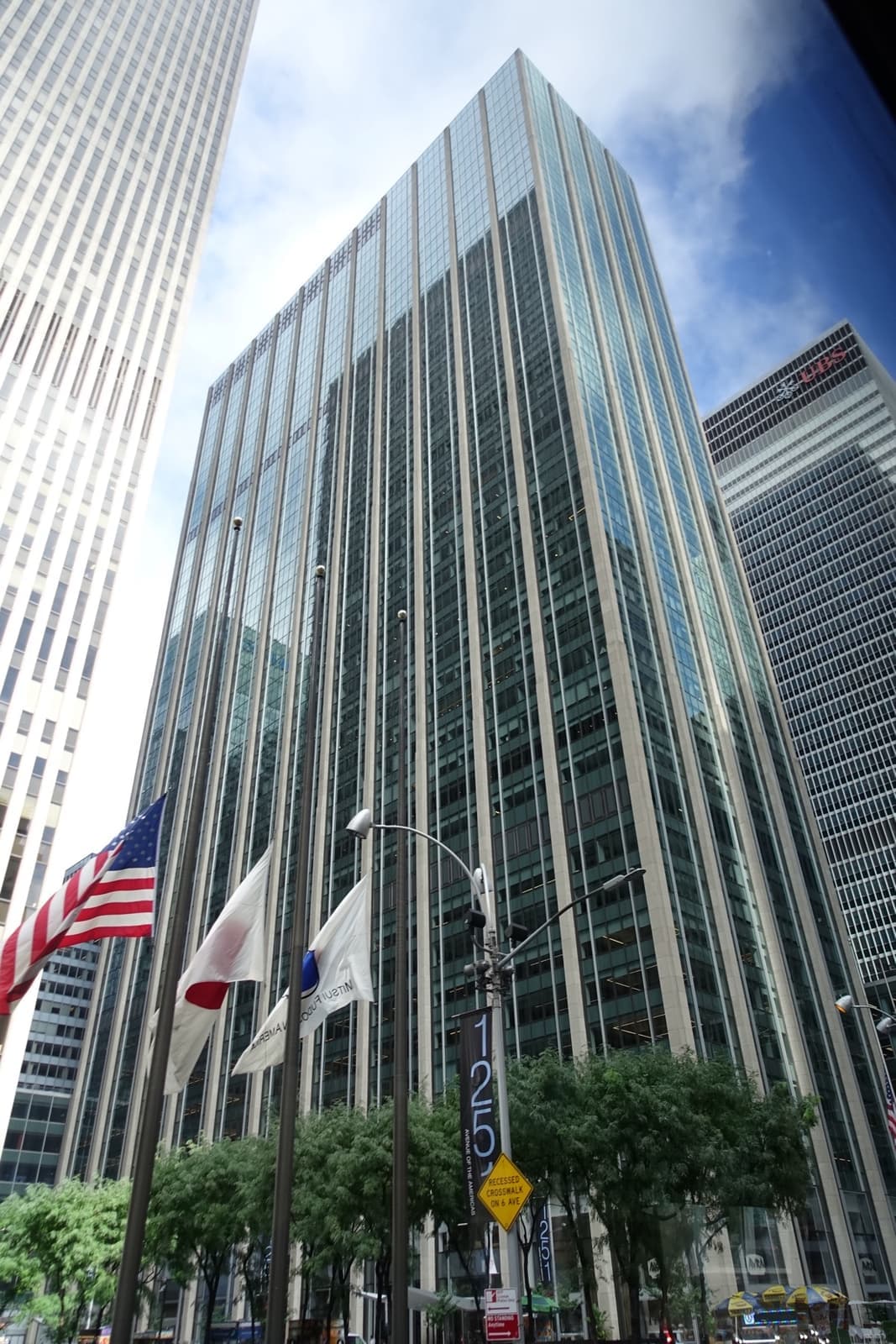 A glass and limestone office tower on Sixth Avenue under blue sky