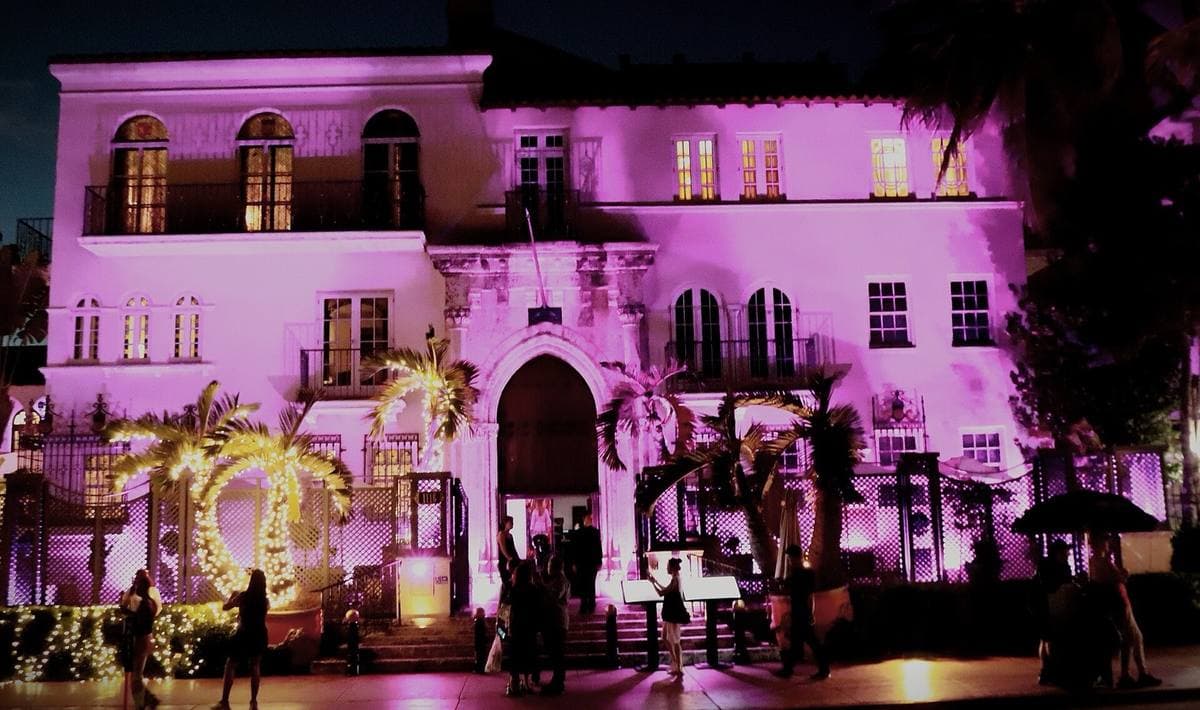 A Mediterranean-style mansion lit pink and violet at night