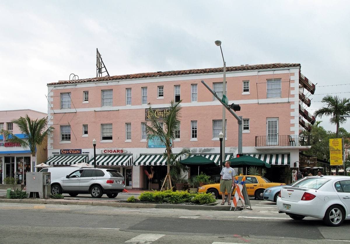 A pink three-storey hotel with striped awnings on a street corner