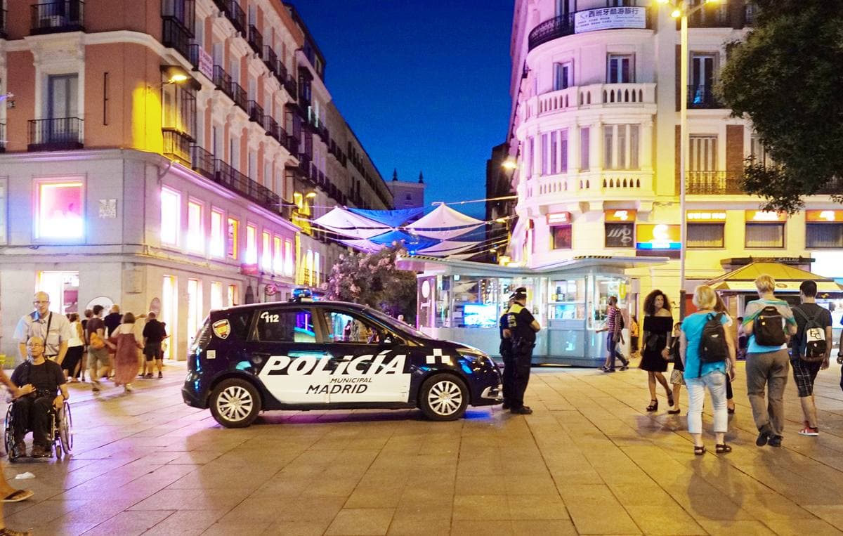 A square at night with lit screens and signs
