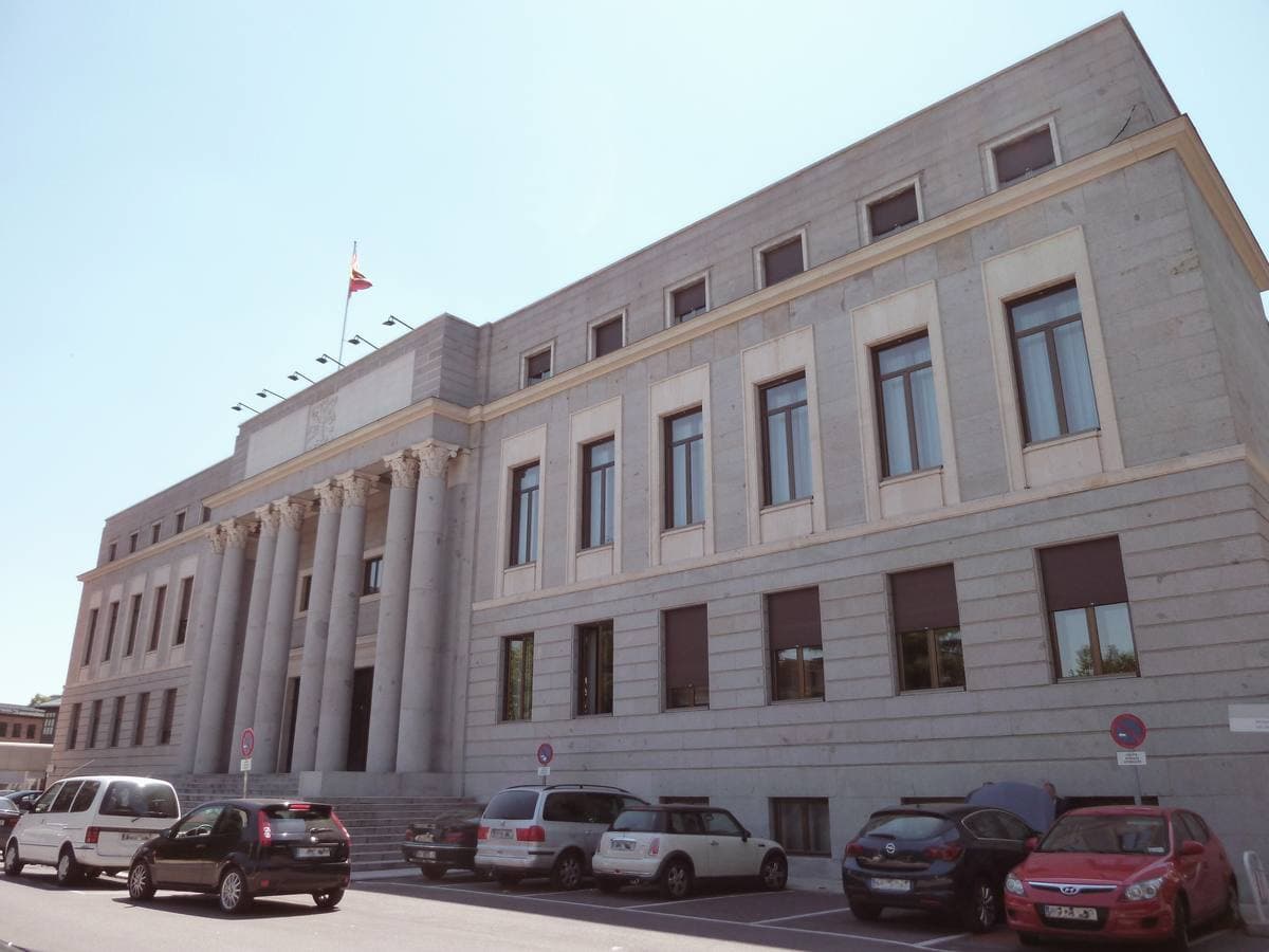 A long pale stone building with a columned centre behind a lawn
