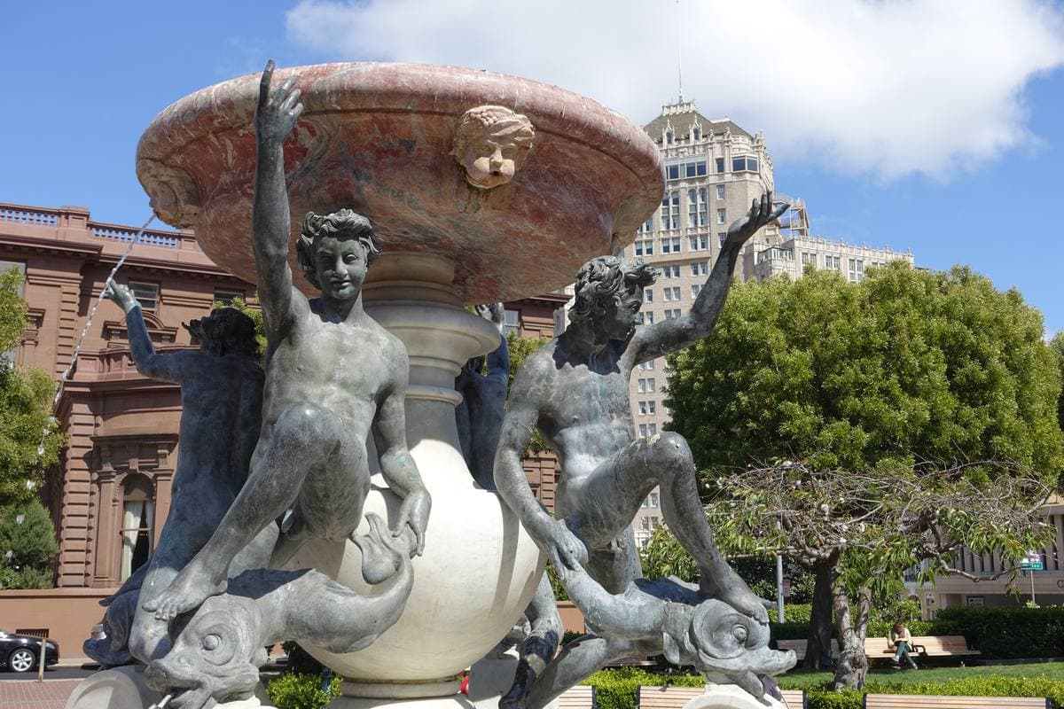 A bronze and marble fountain with figures and tortoises in a park