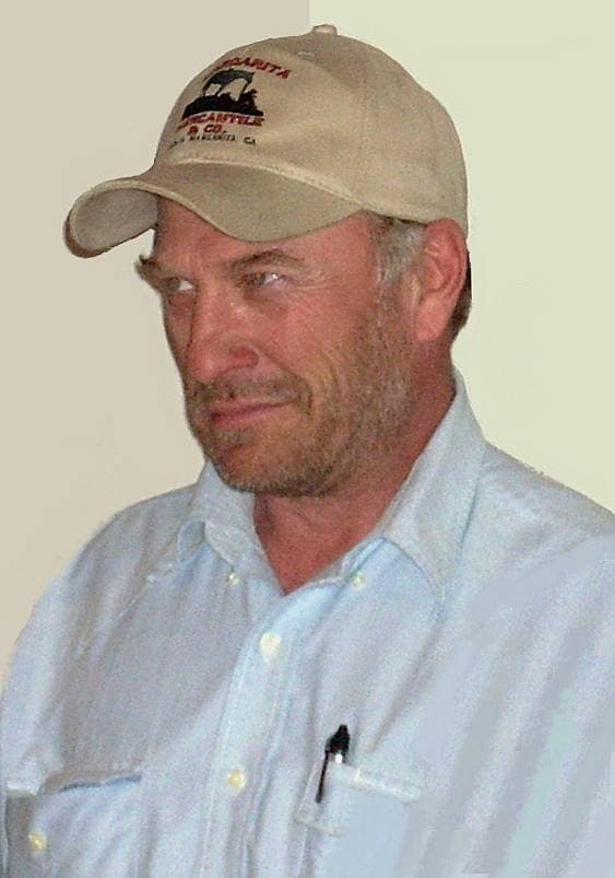 Ted Levine in a baseball cap and light blue shirt