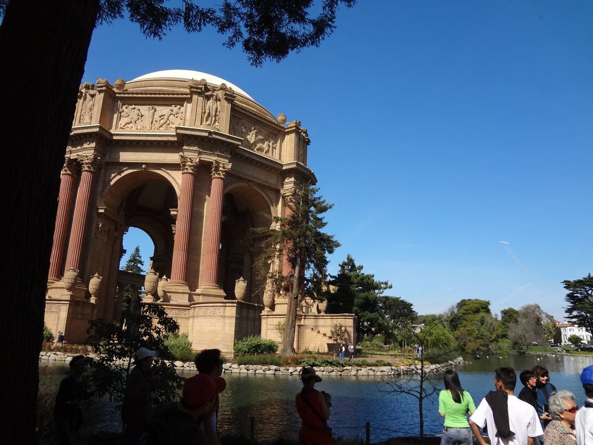 A domed classical rotunda behind trees, with visitors by a lagoon
