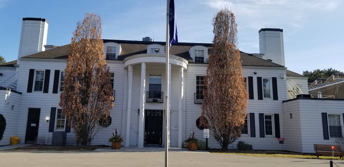 A white colonial-style building with columns and two tall trees