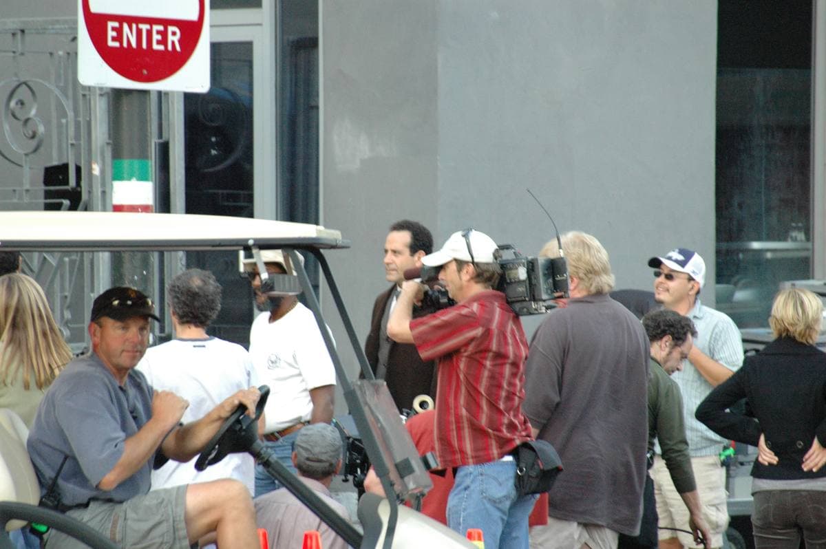 Tony Shalhoub standing among crew members and a camera operator