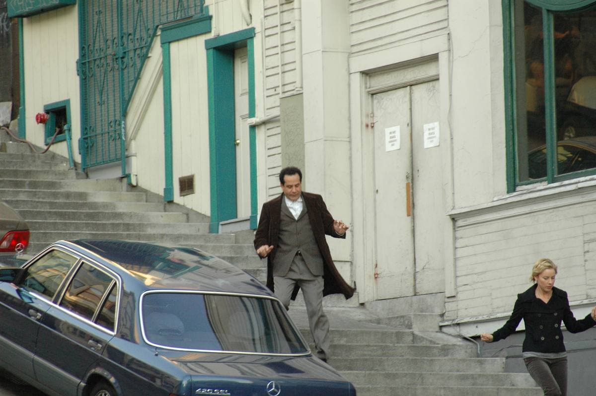 Tony Shalhoub coming down steps while Traylor Howard waits at the side