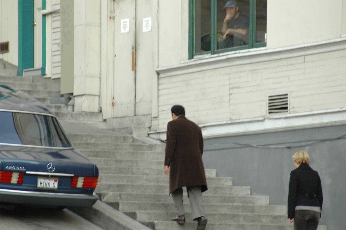 Two actors walking up a concrete stairway past a parked Mercedes
