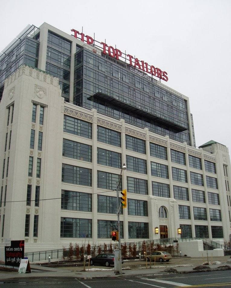 A white 1920s factory building with TIP TOP TAILORS on its roof