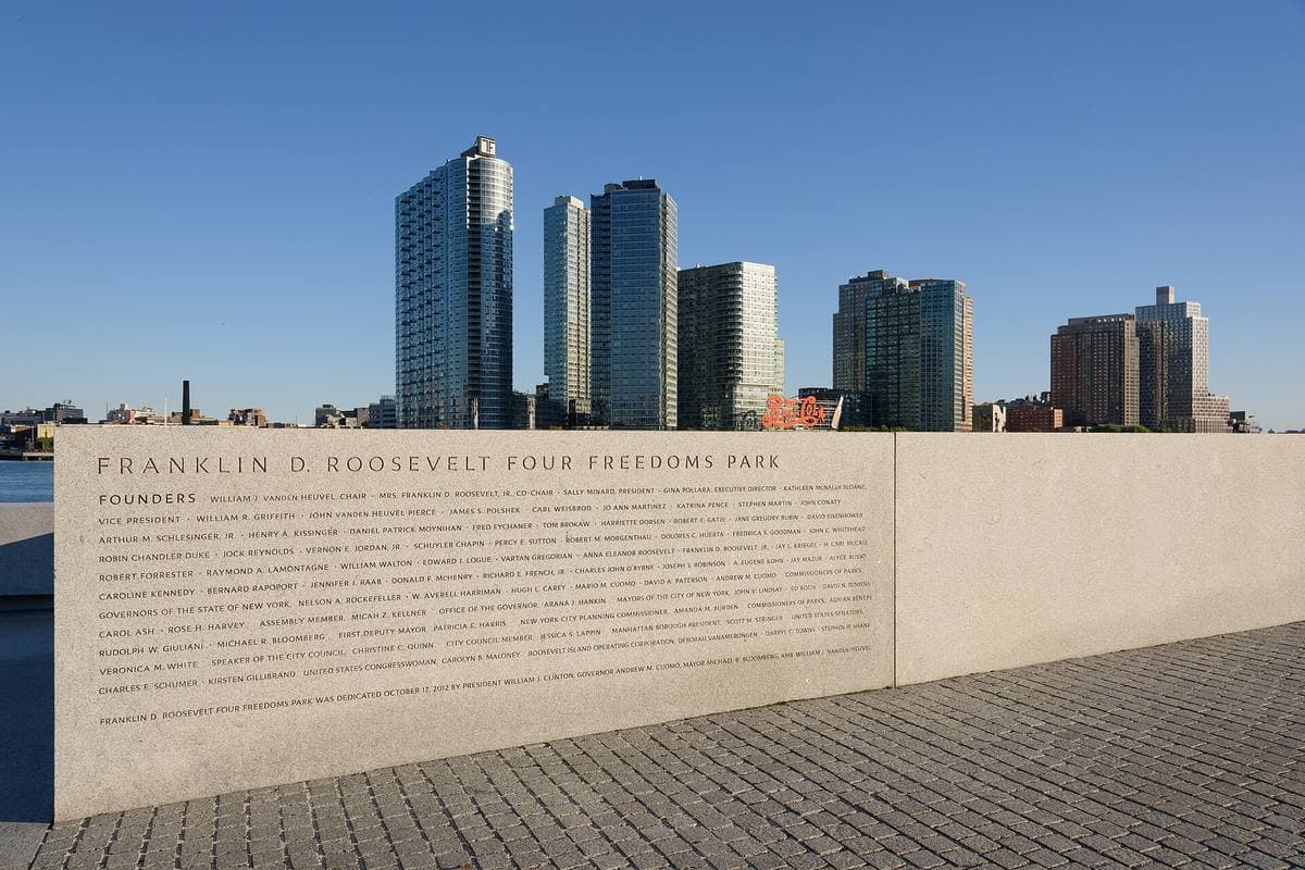 Granite walls and a lawn narrowing towards the river and the Manhattan skyline