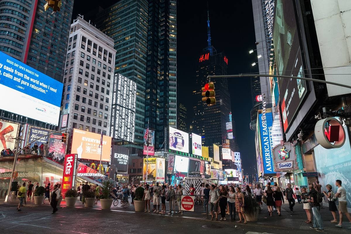 Times Square at night, crowds under lit advertising screens