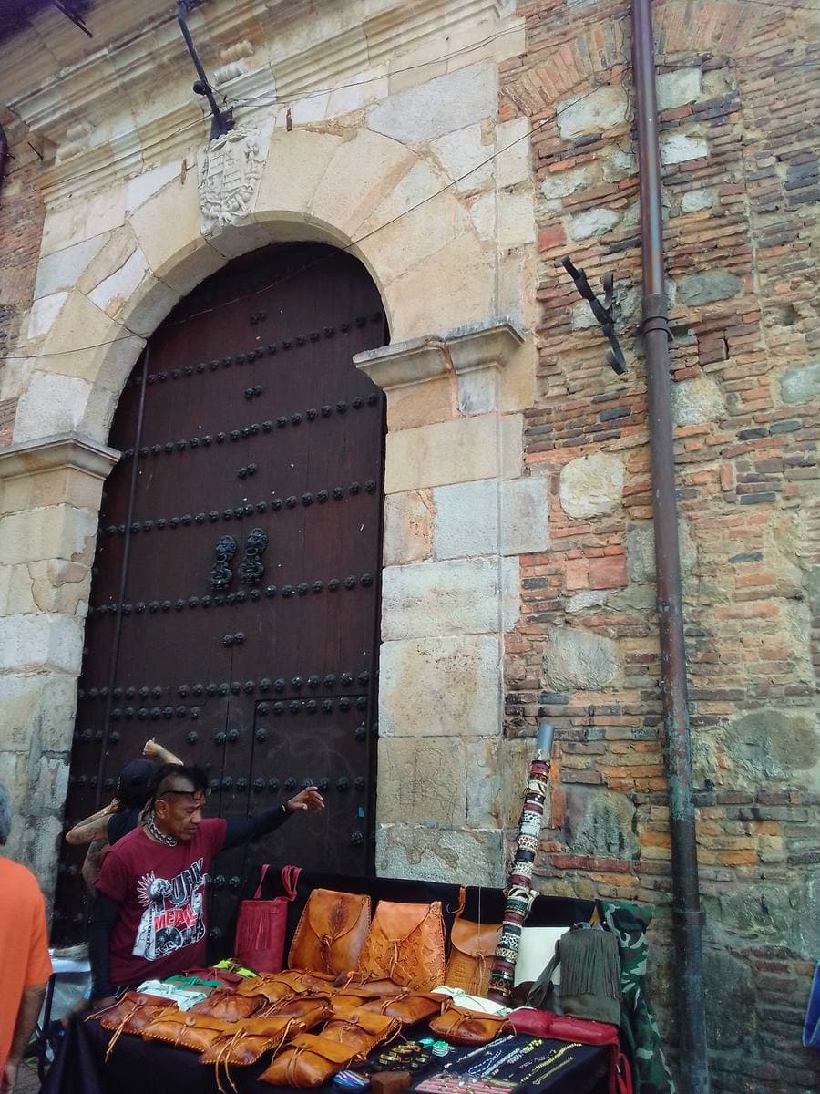 A carved stone church doorway on Calle 11, with a street stall in front