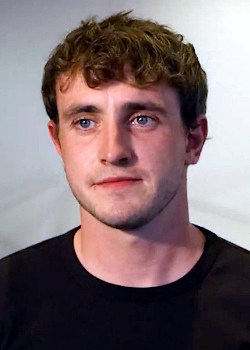 Paul Mescal with curly hair in a black T-shirt, looking just past the camera
