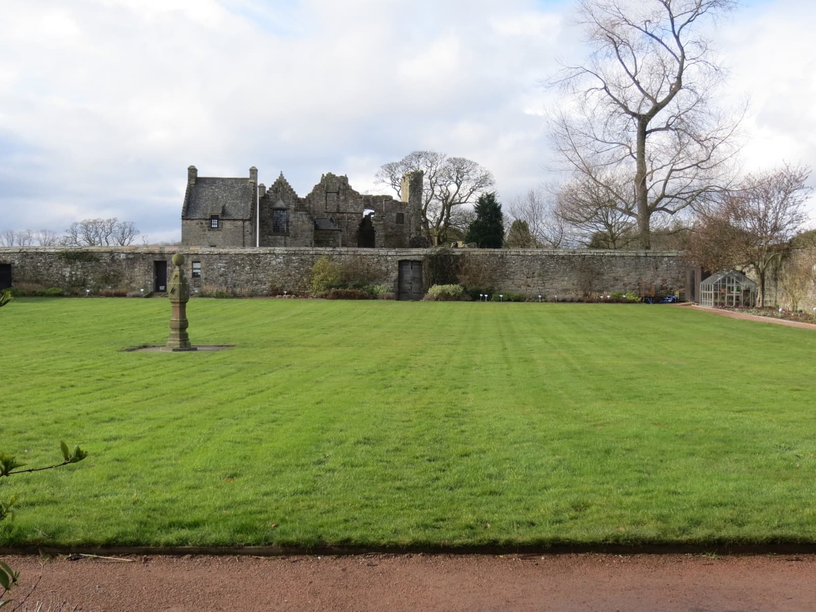 The ruined range of Aberdour Castle behind a walled lawn
